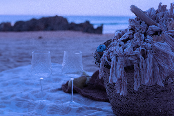 Two wine glasses on the beach at dusk