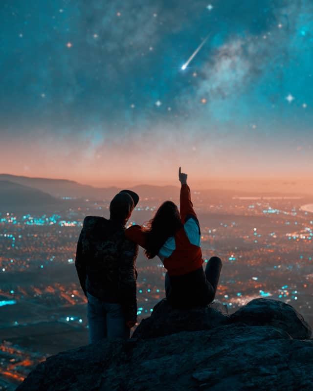 Couple stargazing, pointing at meteor