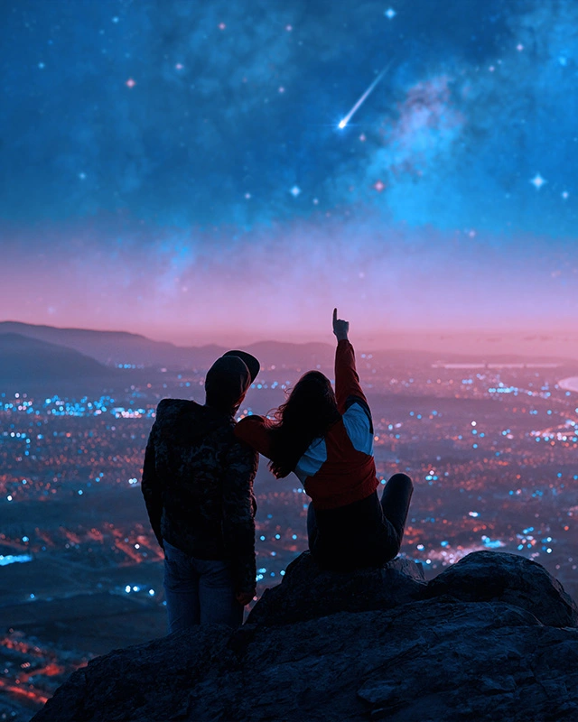 Couple stargazing, pointing at meteor